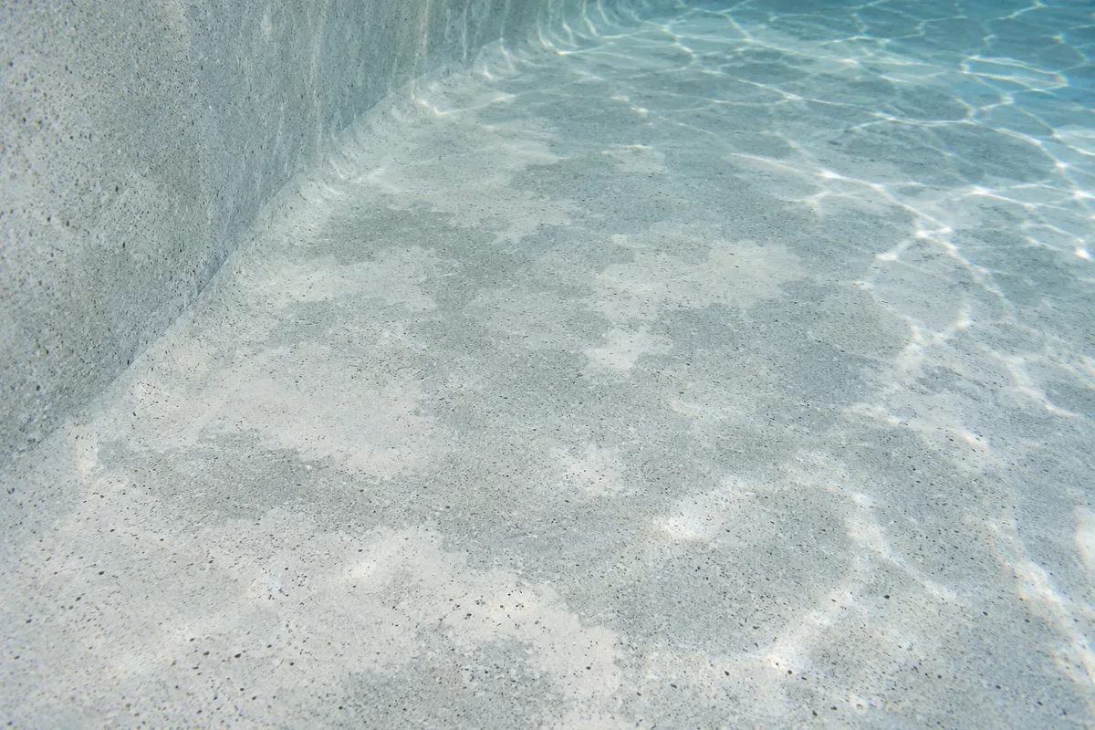 Pale pool finish under clear water with soft, cloudy lighter and darker patches