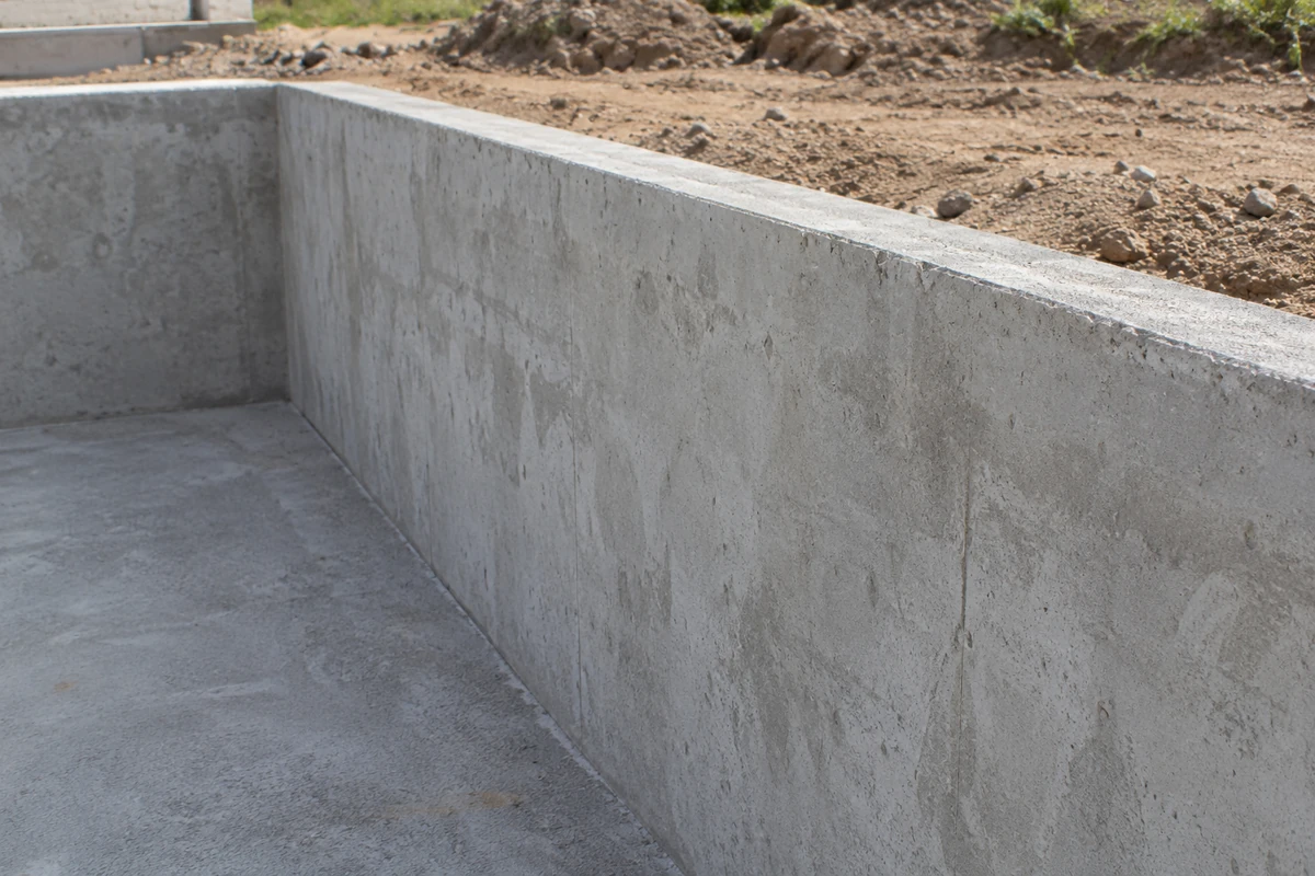 Unfinished concrete at the top edge and upper wall of an empty pool shell before tile or coping
